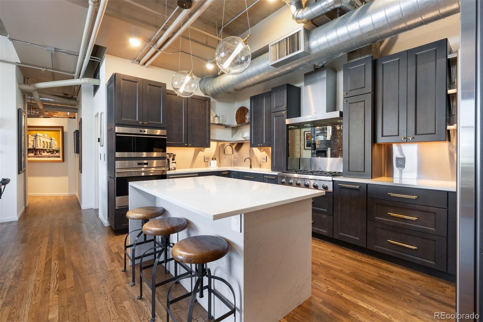 1801 Wynkoop Street, Unit 603 Denver, CO 80202 - Photo 3 of 40 a kitchen with stainless steel appliances kitchen island granite countertop a table chairs in it and wooden floors