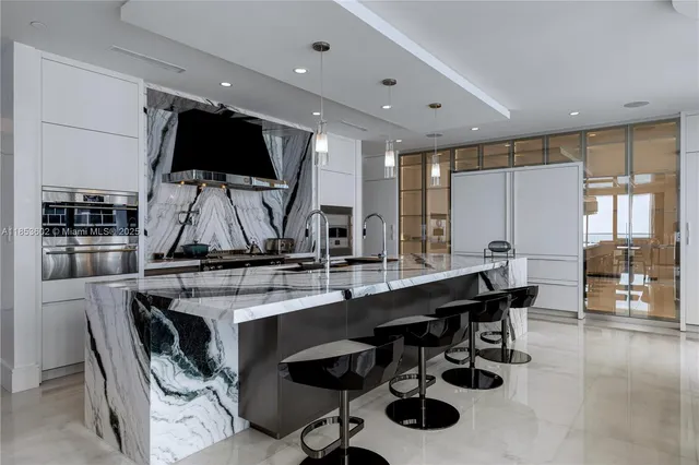 a view of a kitchen with kitchen island stainless steel appliances a sink and a counter top space