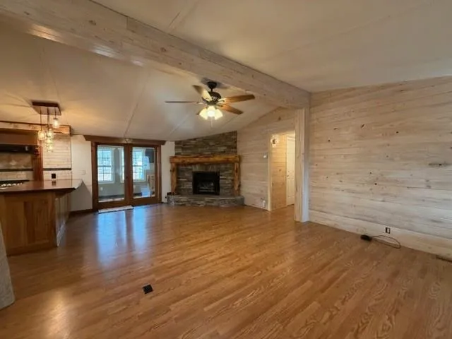an empty room with wooden floor fireplace and windows