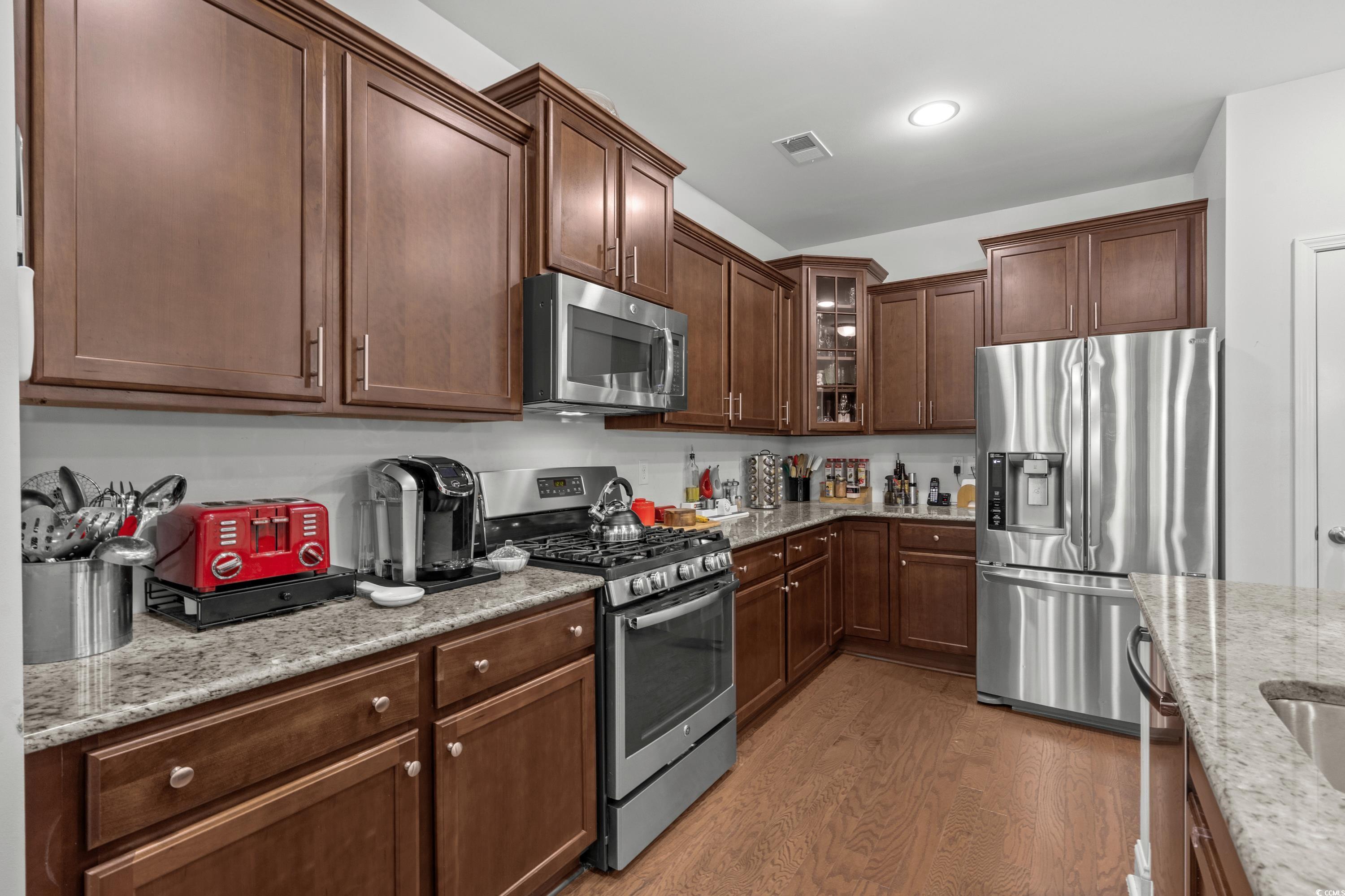 4246 Livorn Loop Myrtle Beach, SC 29579 - Photo 13 of 40 Kitchen with light wood finished floors, stainless steel appliances, light stone countertops, and visible vents