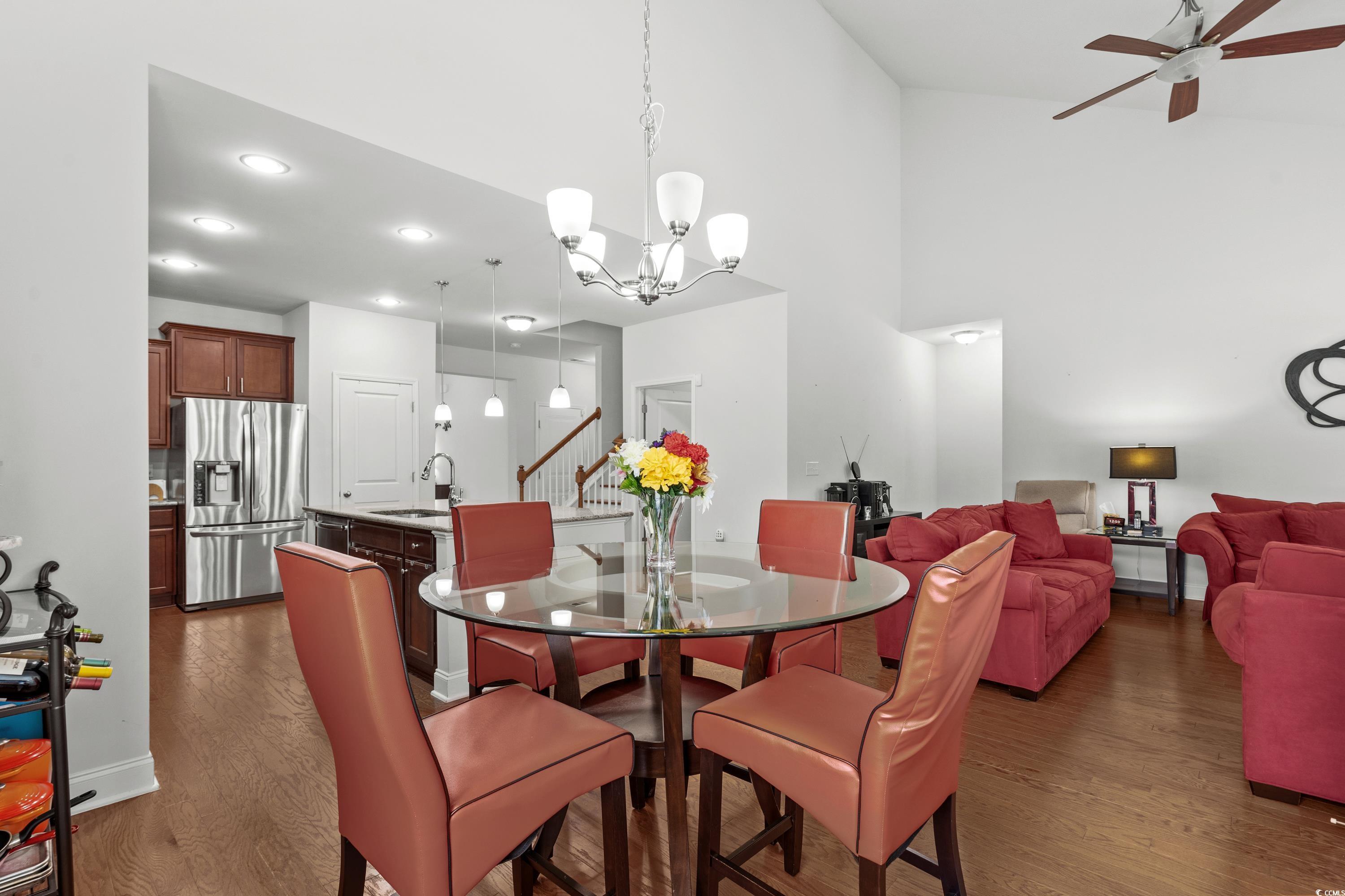 4246 Livorn Loop Myrtle Beach, SC 29579 - Photo 15 of 40 Dining room with ceiling fan with notable chandelier, a high ceiling, dark wood-type flooring, baseboards, and stairway