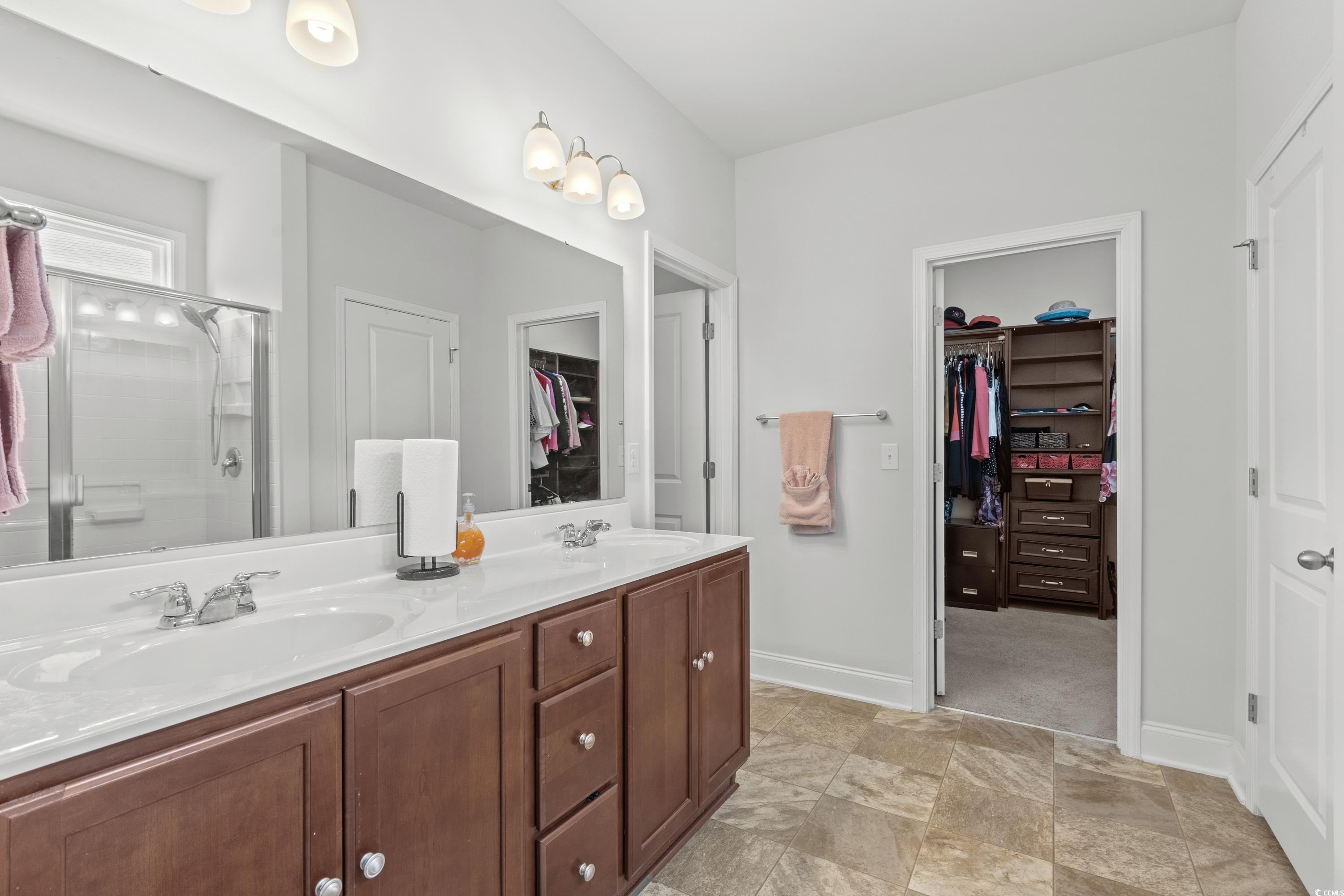 4246 Livorn Loop Myrtle Beach, SC 29579 - Photo 18 of 40 Full bathroom featuring a shower with shower door, double vanity, a sink, and a walk in closet
