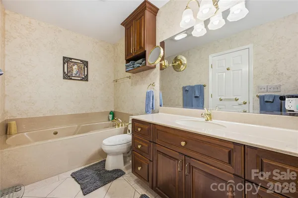 a bathroom with a granite countertop sink a toilet a mirror and bathtub