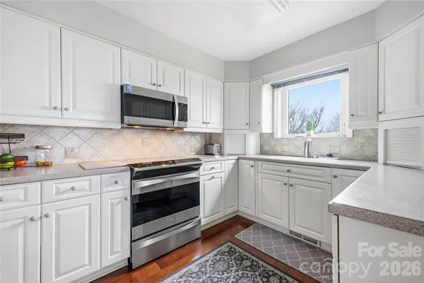 a kitchen with granite countertop white cabinets stainless steel appliances and a window