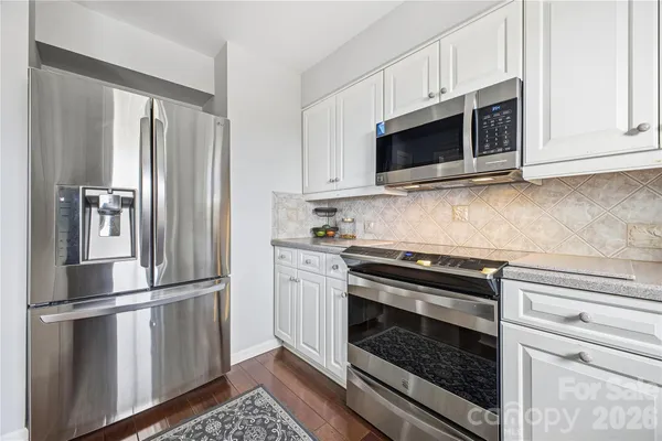 a kitchen with stainless steel appliances white cabinets white stove and a microwave