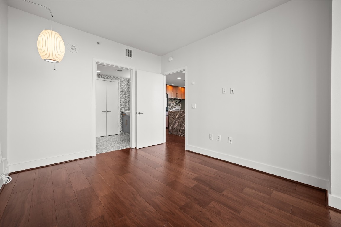 300 Bowie Street, Unit 2405 Austin, TX 78703 - Photo 17 of 39 an empty room with wooden floor and mirror