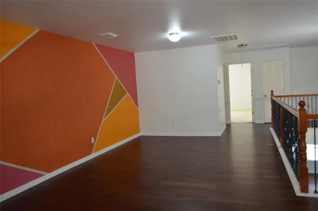 an empty room with wooden floor and staircase