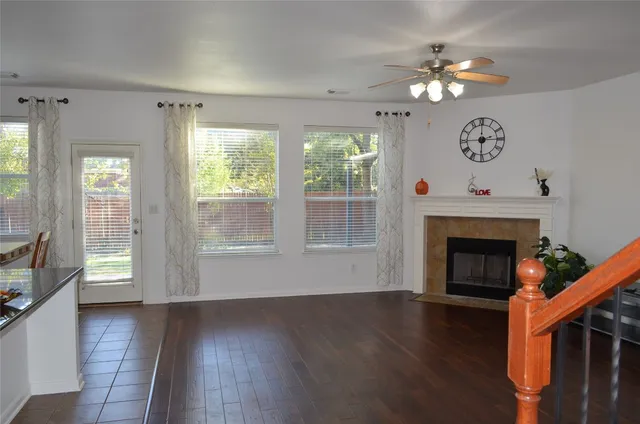 a view of an empty room with wooden floor fireplace and a window