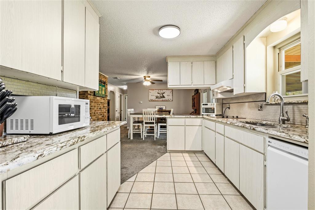 235 Magnus Road Denison, TX 75021 - Photo 24 of 35 a kitchen with stainless steel appliances granite countertop a stove a sink and a microwave