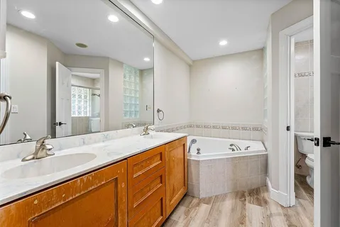 a spacious bathroom with a double vanity sink mirror and bathtub