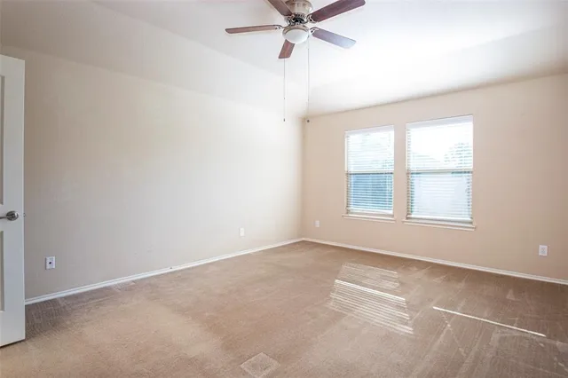 an empty room with a window and a fan
