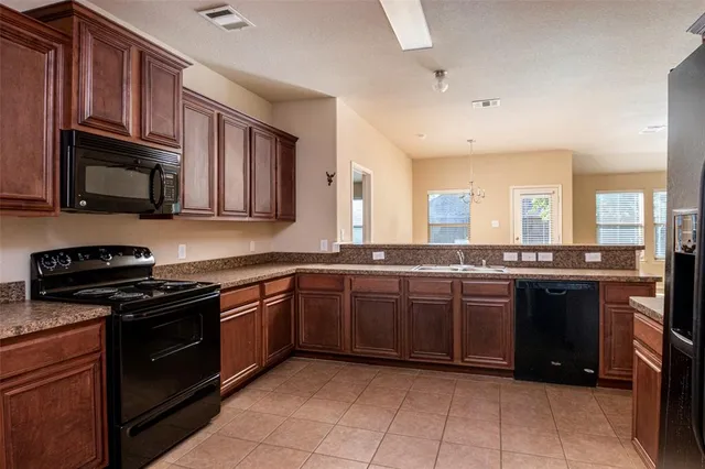 a large kitchen with stainless steel appliances granite countertop a stove top oven a sink dishwasher and granite counter space