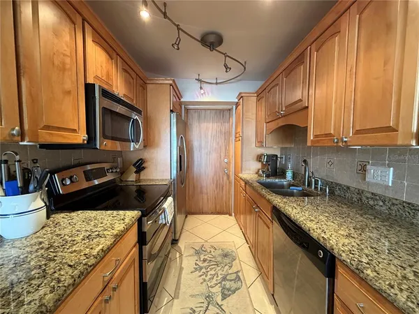a kitchen with granite countertop stainless steel appliances a stove sink microwave and cabinets