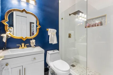 a bathroom with a toilet sink vanity shower and mirror