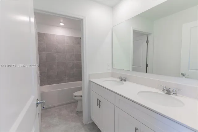 a bathroom with a bathtub shower sink vanity mirror and toilet