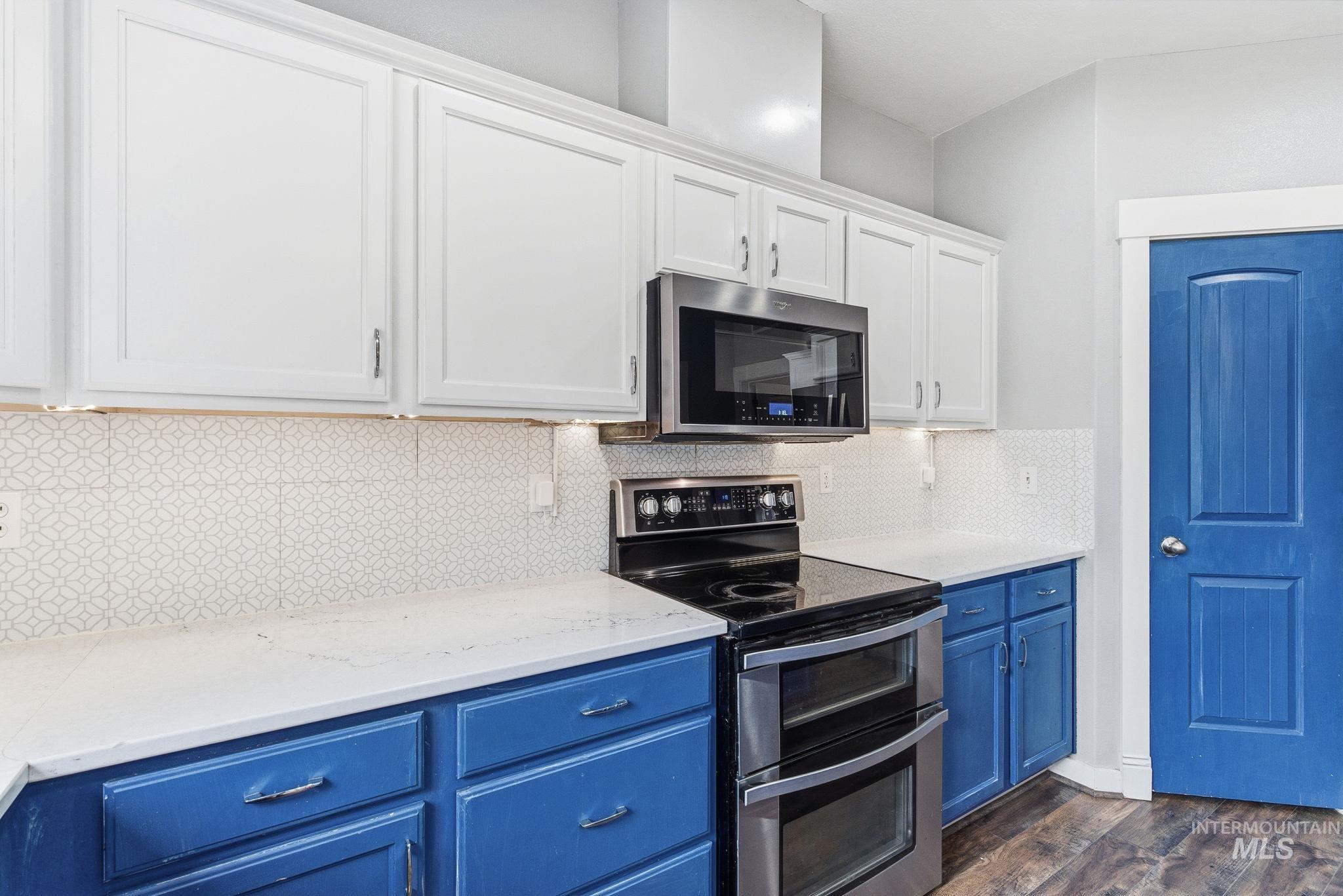 2520 Summercrest Street Caldwell, ID 83607 - Photo 13 of 42 Kitchen with blue cabinets, stainless steel appliances, white cabinets, dark wood-style floors, and decorative backsplash
