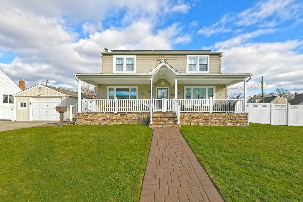 View of front of home with a front yard, a porch, a garage, and an outdoor structure