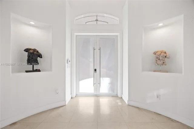 a view of a hallway with white walls and chandelier