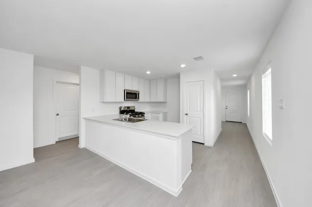 a view of a kitchen with kitchen island a sink a stove and a refrigerator