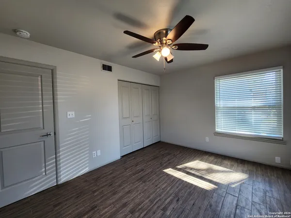 a view of empty room with wooden floor and fan