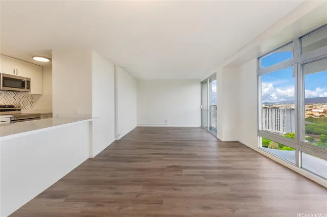 a view of an empty room with kitchen and a window