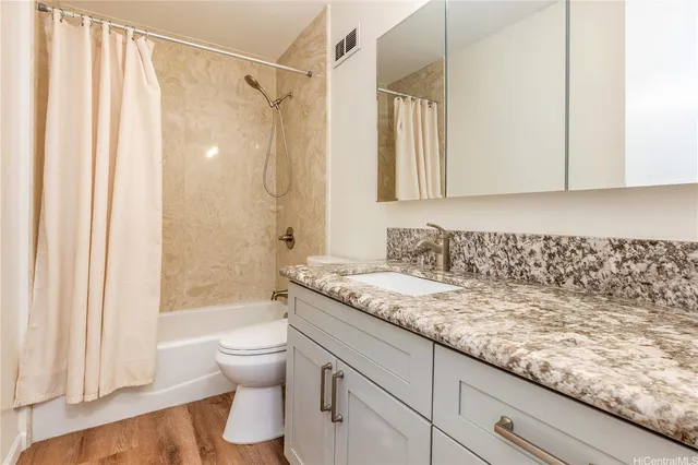 a bathroom with a granite countertop sink a toilet and shower