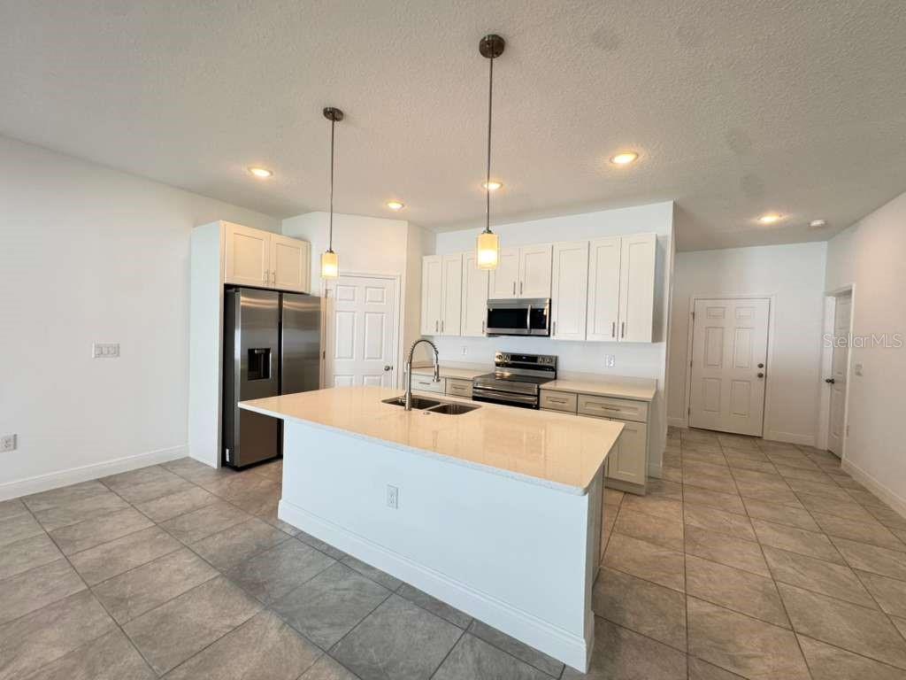 16054 Southwest 55th Avenue Road Ocala, FL 34473 - Photo 15 of 58 a large kitchen with stainless steel appliances kitchen island granite countertop a refrigerator a sink and a stove