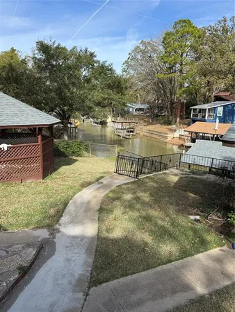a view of a park with large trees and cars parked in front of it