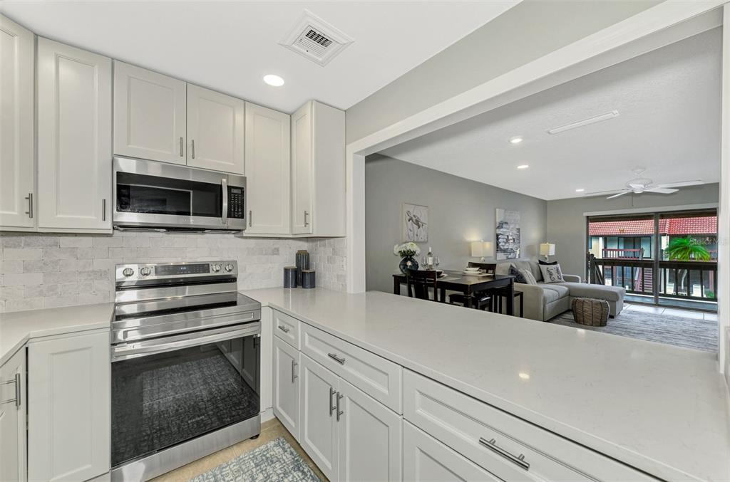 1618 Stickney Point Road, Unit 1618202 Sarasota, FL 34231 - Photo 24 of 58 a kitchen with stainless steel appliances a stove microwave and cabinets