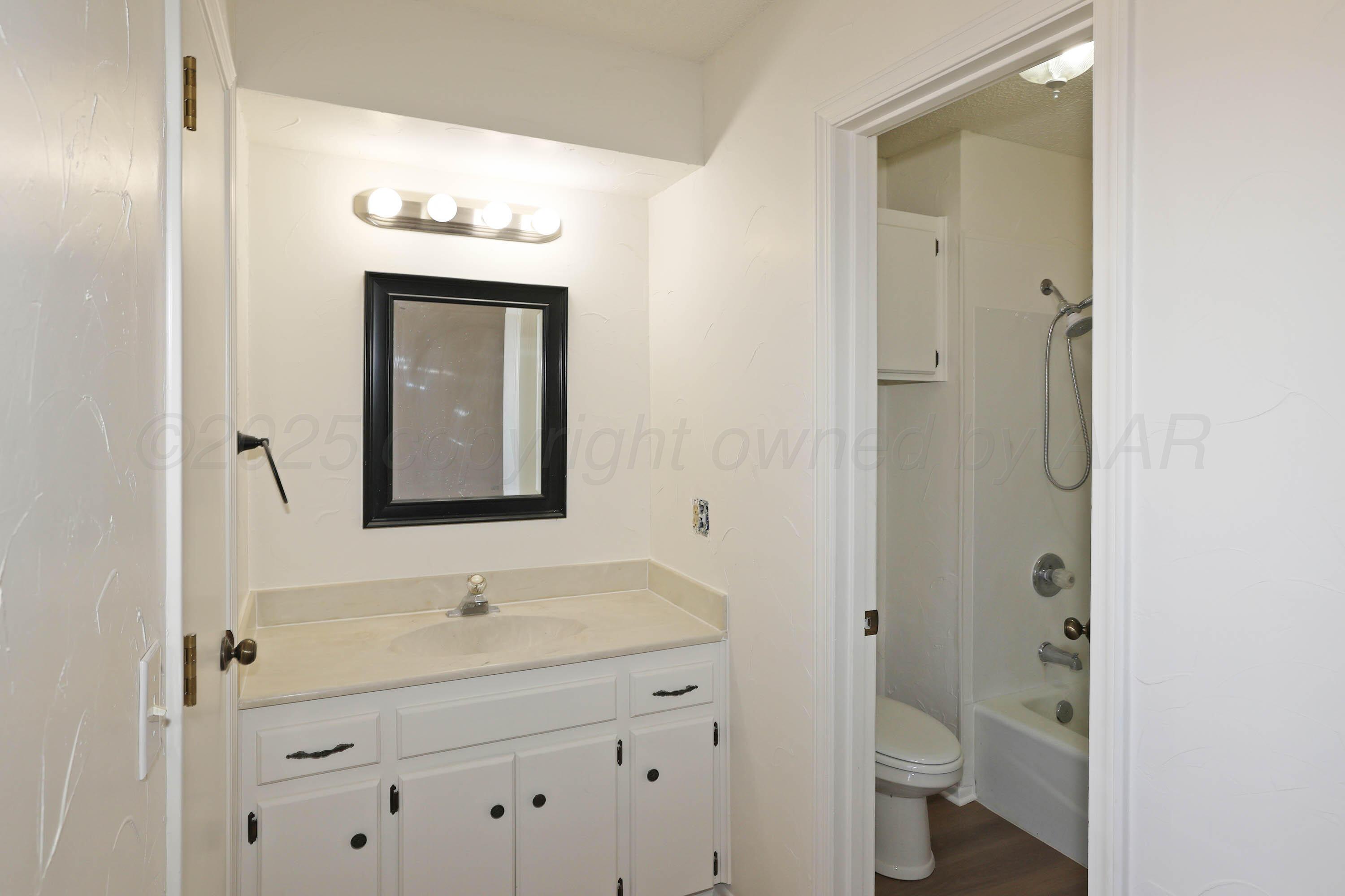 4415 Kingston Road Amarillo, TX 79109 - Photo 14 of 28 a bathroom with a toilet a sink and mirror