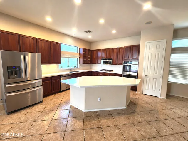 a kitchen with stainless steel appliances granite countertop a refrigerator a sink a stove a microwave and cabinets