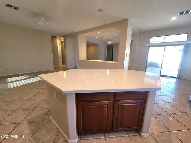 a view of an empty room with window and chandelier fan