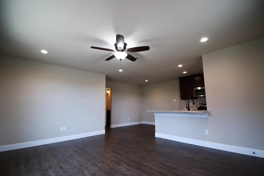 an empty space with a ceiling fan and wooden floor