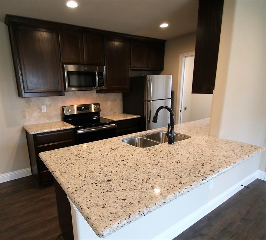 156 Crossbow Court Weatherford, TX 76088 - Photo 5 of 23 a kitchen with granite countertop a sink and a stove top oven with wooden floor