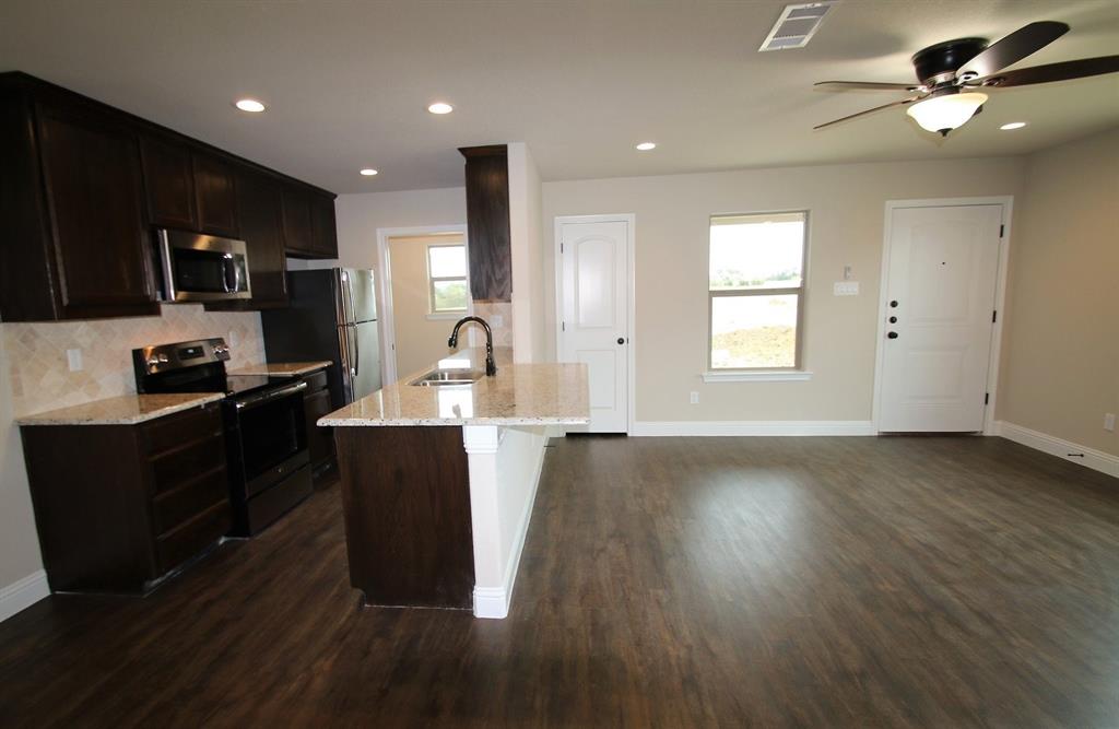 156 Crossbow Court Weatherford, TX 76088 - Photo 6 of 23 a kitchen with stainless steel appliances granite countertop a refrigerator a sink dishwasher a stove and black cabinets with wooden floor