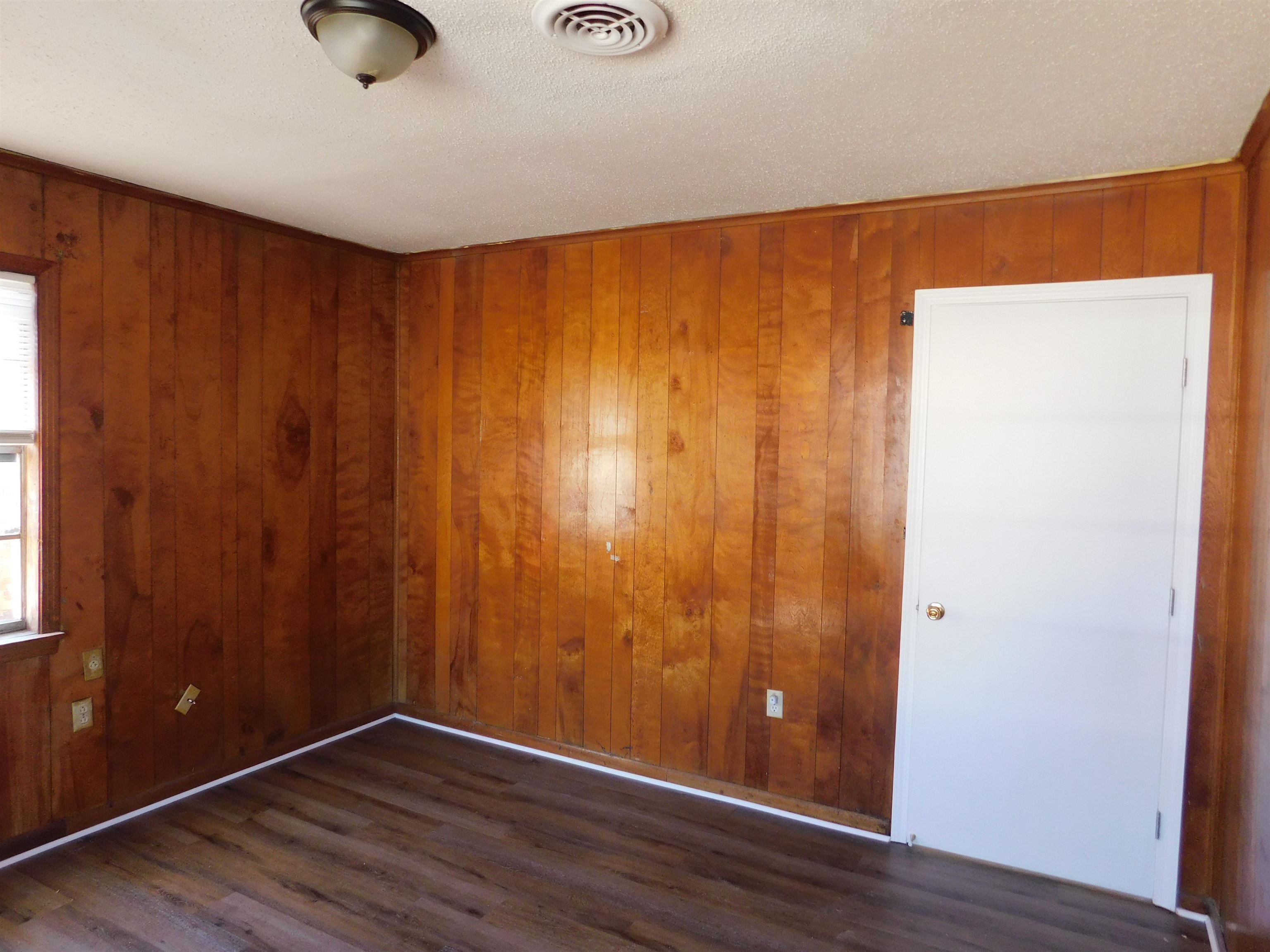 2367 Hubbard Avenue Memphis, TN 38108 - Photo 8 of 8 Spare room featuring wooden walls, dark wood finished floors, and a textured ceiling