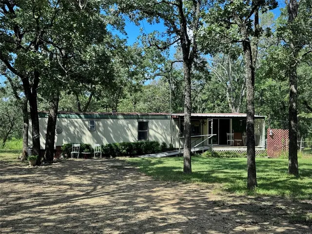 a view of a house with backyard and trees