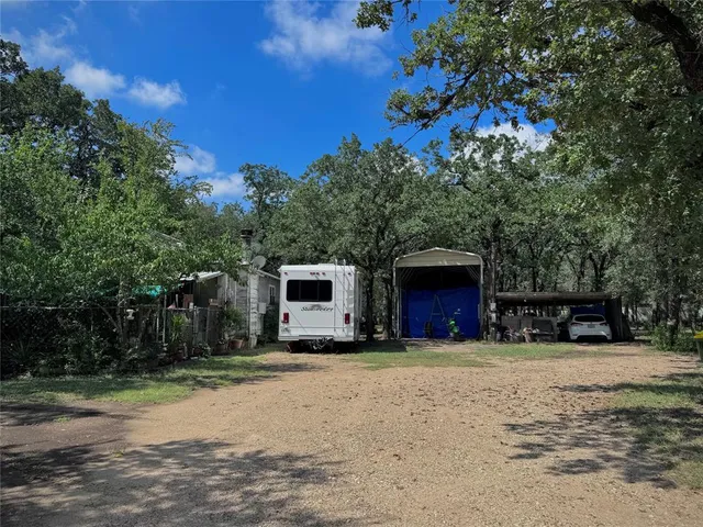 a view of house with outdoor space and trees in the background
