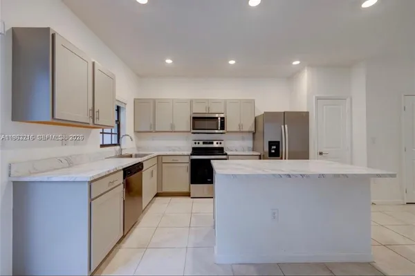 a kitchen with stainless steel appliances granite countertop a stove top oven a sink and a refrigerator