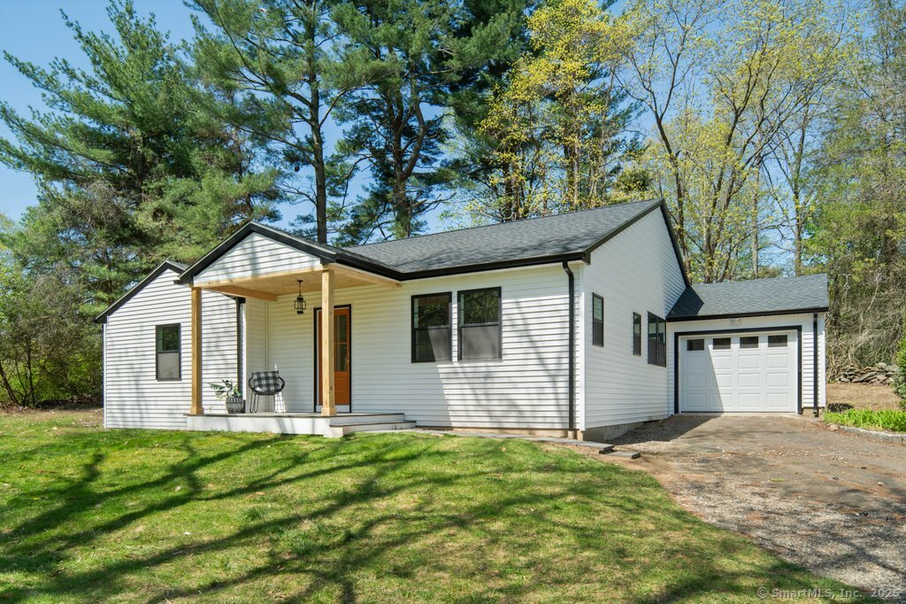 a front view of house with yard and trees in the background