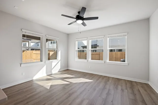 a view of empty room with wooden floor and fan