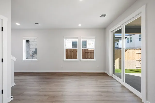 a view of an empty room with a window and wooden floor