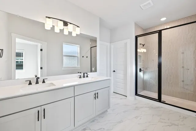 a bathroom with a double vanity sink mirror and shower