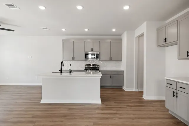 a kitchen with stainless steel appliances granite countertop a white cabinets a sink a stove a refrigerator and a microwave