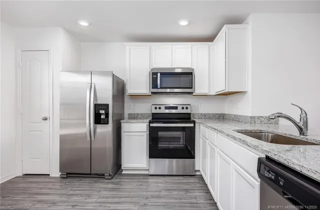 a kitchen with granite countertop a refrigerator sink and microwave
