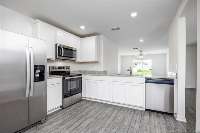 a kitchen with cabinets stainless steel appliances a sink and wooden floor