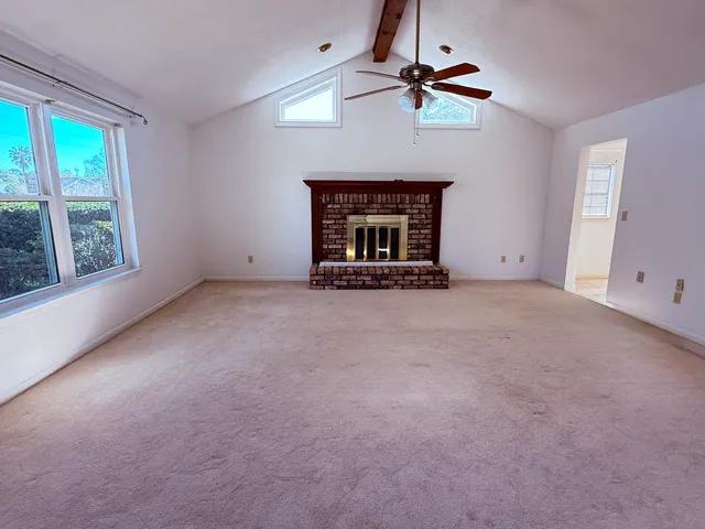 an empty room with chandelier fan and windows