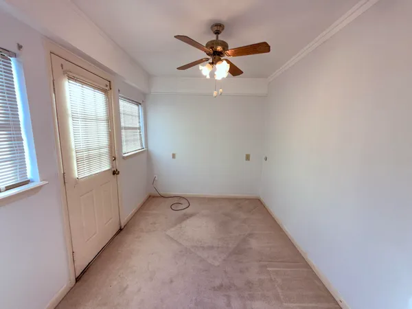 an empty room with chandelier fan and windows