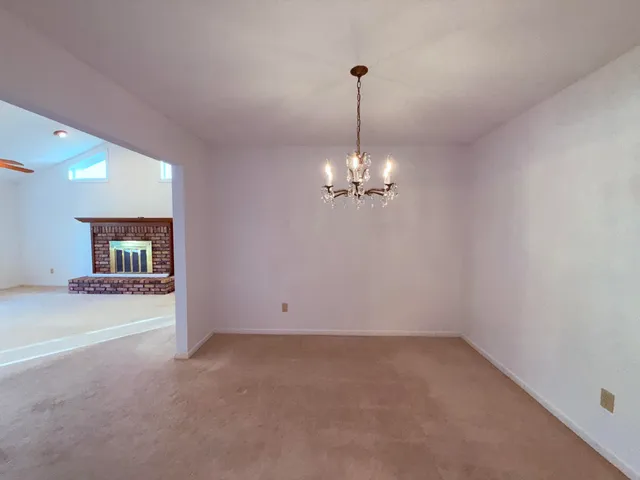an empty room with a chandelier fan and windows