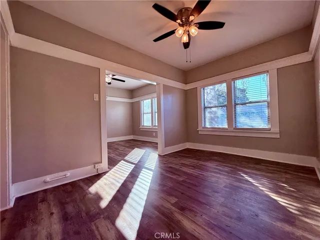 a view of an empty room with window and wooden floor